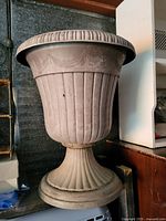 Large decorative planter urn with fluted body and rope swag design near the rim on pedestal base
