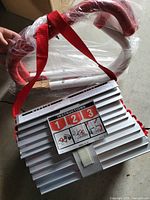 Folded fire escape ladder with visible instruction label and red hooks