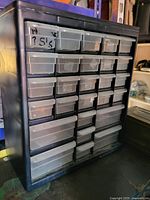 Black screw organizer showing multiple clear plastic drawers in a 7x4 arrangement with varying drawer sizes, used for storing screws and small parts.