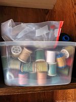 Plastic container filled with many spools of thread in a variety of colors