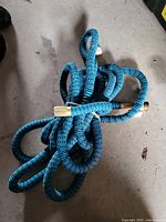 Blue expandable garden hose with brass fittings on a concrete floor.