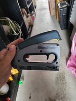 Photo of SureEdge handheld stapler showing metal body and blue handle