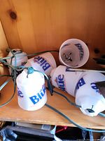 Close-up photo of the Bud Light beer can string lights showing several white plastic beer can covers with Bud Light logo with bulbs inside on a green wire.