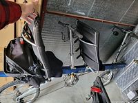 Blue step-through tandem bicycle frame with dual saddles and pedals, handlebar removed and held by hand