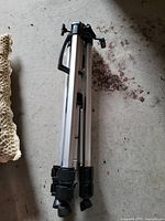 Photo of folded aluminum tripod showing legs with black plastic locks and carry handle.