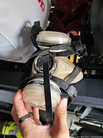 Front and side view of Honeywell rubber venting respirator mask with two attached round filter cartridges and adjustable black straps.