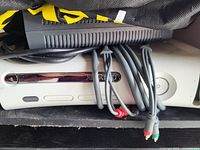 Photo of white Xbox 360 console with black power supply and AV cables