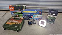 Full lot overview showing all boxed items and loose fishing reel and LED light