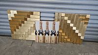 Two gold wood sculptural wall art panels with stepped geometric designs and one Moët & Chandon rectangular decor panel with champagne bottle images, all positioned against a metal shutter.