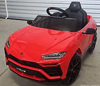 Angled front view showing hood, grill, seat and steering wheel of the red ride-on car