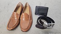 Overview of the lot showing brown leather Cole Haan loafers, black Tumi wallet, and black Banana Republic belt