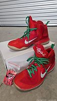 Pair of red and green Nike LeBron 9 basketball shoes size 13.5 with extra red laces in original box.