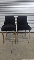 Front view of the two black velvet chairs with gold frames showing overall design and condition.