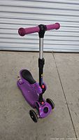 Front and side angle of purple Skidee kids scooter with adjustable T-bar handlebar and foldable seat.