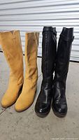 Two pairs of women's mid-calf boots, tan and black, side by side on concrete floor.