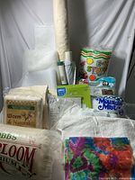Full lot showing multiple bags of polyester fiberfill, quilt batting rolls, fusible fleece, and other materials arranged against a white background.