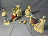 View of entire collection of ceramic and porcelain figurines including two goose bookends, boy and girl figurines, and small chicks.