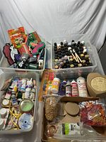 Four plastic bins filled with assorted craft supplies including paints, adhesives, wood cutouts, stamps, embossing powders, foam brushes, glitters and dried natural embellishments.