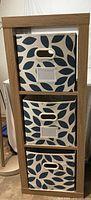 Front view showing three fabric storage bins inside wood-like laminate cube shelf