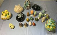 Full collection including porcelain egg boxes, carved stone eggs, painted wood eggs, and egg cups arranged on a flat surface
