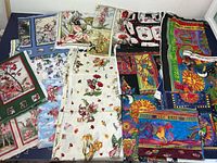 Wide shot of all fabric pieces laid out on a flat surface, showing various floral and fairy prints, including Laurel Burch vibrant patterns and Flower Fairies designs with detailed fairies on floral backgrounds.