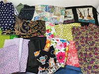 Assorted fabric pieces in various colors and patterns including polka dots, floral prints, solid black, teapots on black, and bright colored florals.