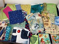 Multiple assorted colorful kid-themed fabric pieces laid out showing dinosaur scenes, animals, rockets, and vehicles.