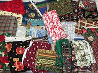Top view of assorted holiday fabrics including prints of poinsettias, plaid patterns, nativity scenes, candy canes, and floral fabrics.