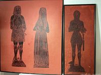 Full view of both framed brass rubbing pictures on orange-red background. Left frame larger with husband and wife, right frame smaller with Robert Fox and dog.