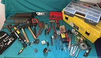 Overview of all hand tools spread out on a blue surface including saws, hammers, wrenches, socket set, yellow toolbox and storage bin with hardware