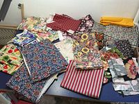 Photo showing an assortment of fabric pieces laid out with floral and patterned designs in various colors including red, blue, yellow, and green