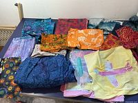 Overall view of assorted quilting fabrics with various batik prints and colors laid out on table.
