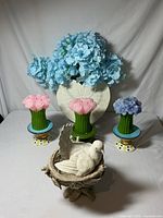 Full view showing colorful flower candles on ceramic stands, heart-shaped vase with light blue artificial flowers, and resin bird nest with ceramic dove figurine.