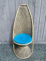 Full view of tall wicker peacock chair with distinctive tall back and blue seat cushion.
