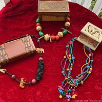 All items displayed together on red cloth background showing two carved wooden boxes and multiple pieces of chunky wood ethnic jewelry