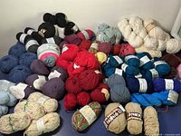 Variety of yarn skeins and balls in multiple colors arranged on a surface.