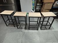 Four bar stools arranged in a row, showing metal frame structure and light wood-look rectangular seats.
