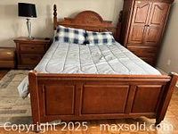 Bed with mattress and matching nightstand with lamp on top in bedroom.