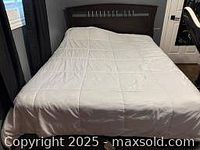 Chocolate brown queen size bed with a wooden headboard featuring vertical slats and white bedding.