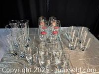 Photo showing 4 Stella Artois stemmed glasses with logo and additional clear glasses behind