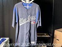 Front view of Blue Jays button-up jersey with visible Blue Jays logo and 'Blue Jays' script lettering.