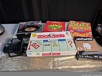 Photo of six board games laid out on a table showing front and top of the boxes.