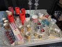 Wide shot of the lot showing many red pillar candles, gold votive holders, jar candles, clear glass holders, and red tealights