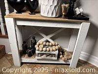 Front view of wooden console table showing natural wood top and white X-back design frame
