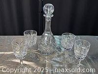 Crystal decanter and four stemmed goblets arranged in a line, showing item details and size.