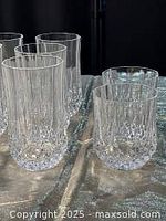 Photo showing six tall crystal highball glasses and four shorter matching crystal whisky glasses with vertical cut patterns.