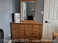 Eight drawer wooden dresser with metal handles, natural wood finish, shown in front of a closed door with a small mirrored jewelry box on top (items on dresser not included).