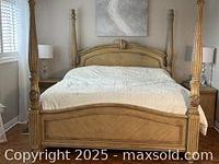 Photo of large wooden four poster bed with carved posts, curved headboard, and footboard, light wood finish
