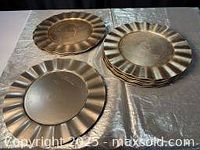Photo showing multiple gold coloured charger plates stacked and laid out to display bevelled rim detail