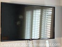 Front view of the 40-inch LG television powered off with window blinds reflection on the screen.